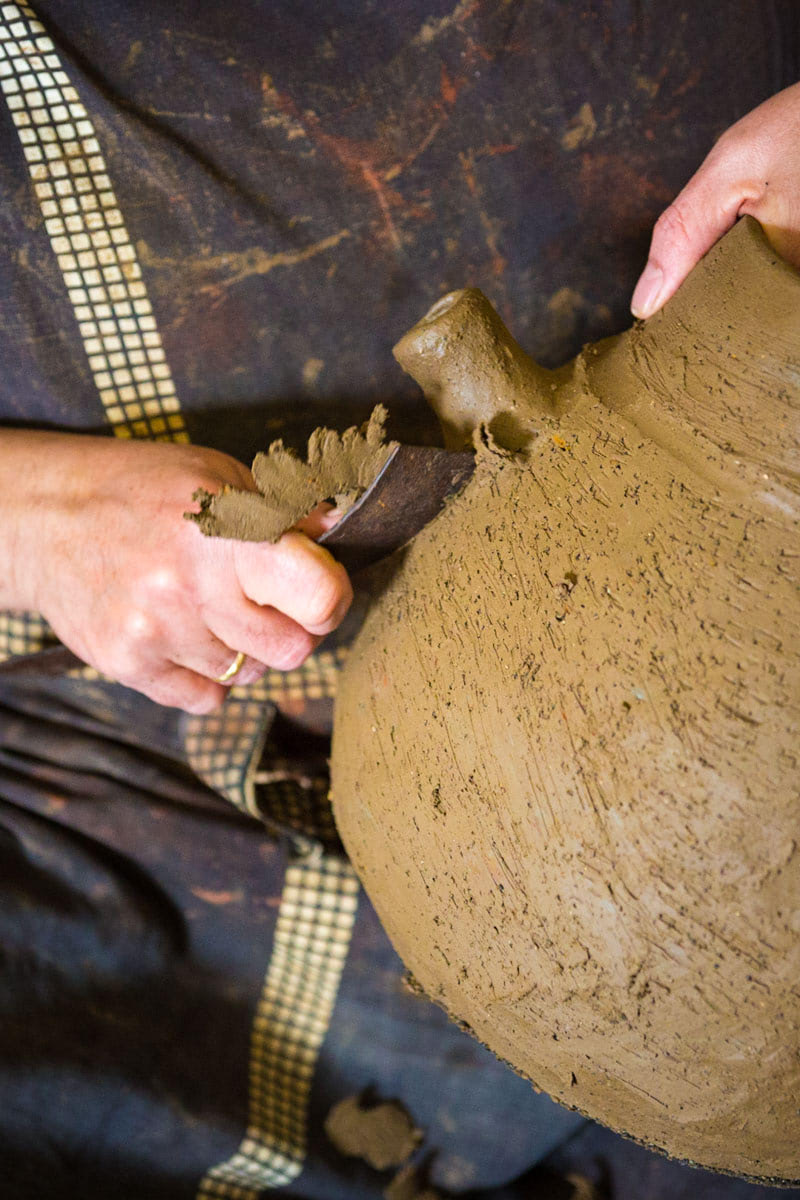 Mujer trabajando el barro para hacer una vasija de cerámica.